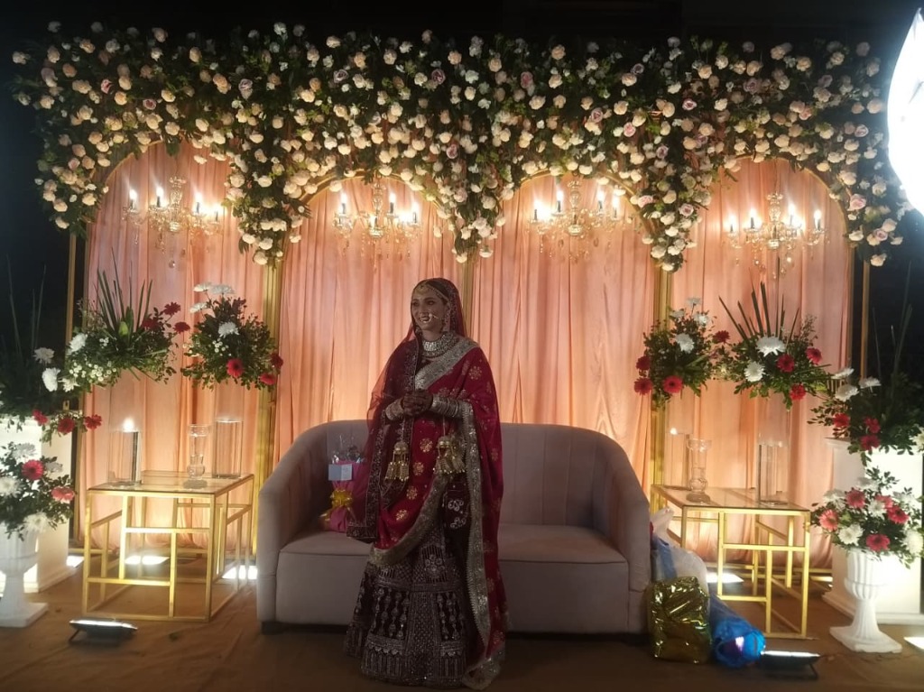 Beautiful bride on stage with extensive floral ceiling and chandeliers - Your dream wedding awaits