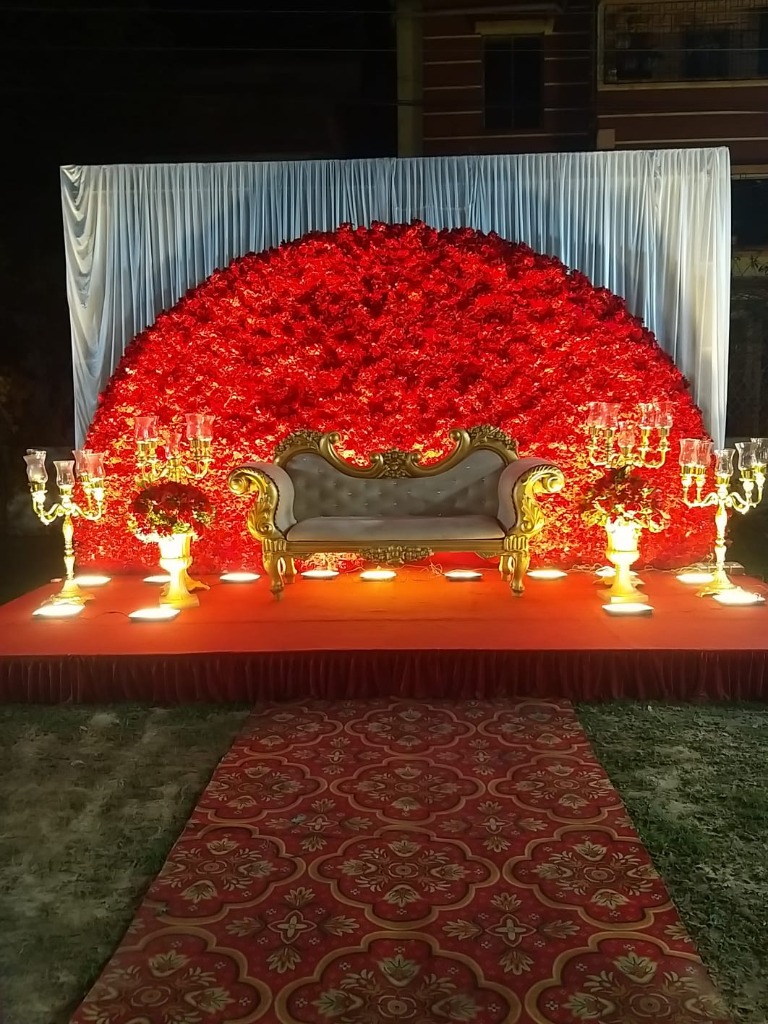 Dramatic red rose fan stage setup with golden candelabras and elegant furniture