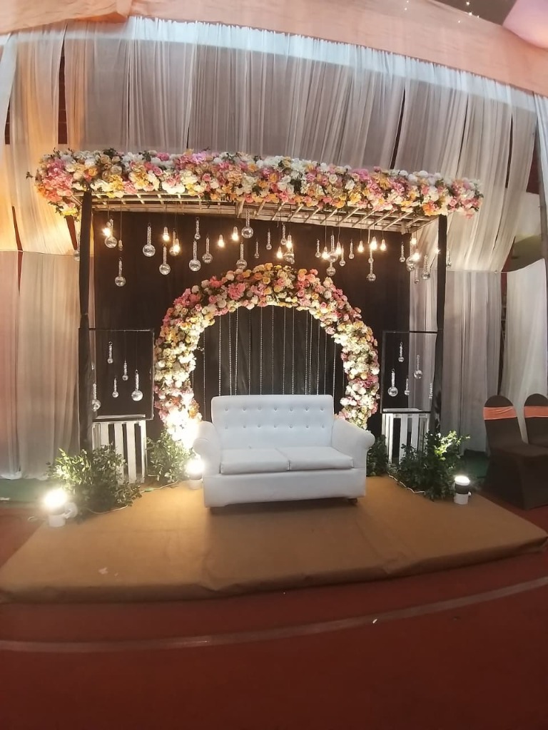 Elegant white stage setup with crystal hangings and floral arch